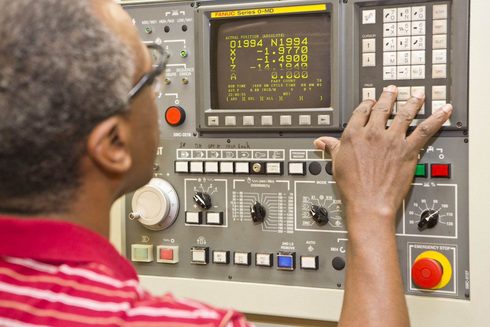 Machinist operating FANUC CNC control in a manufacturing facility